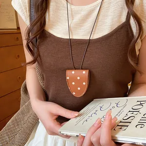 Detail einer braunen Leder-Brillenclip-Halskette mit Punkten, getragen als Accessoire.
