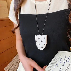 Detailansicht eines weißen Polka-Dot-Lederbrillenclips an einer langen schwarzen Kordel