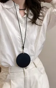 Detailansicht einer minimalistischen schwarzen Lederhalskette mit rundem Anhänger