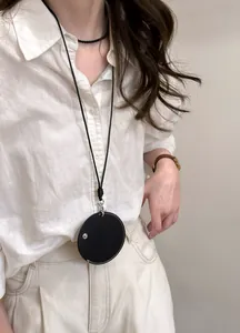 Detail eines minimalistischen schwarzen Lederhalskette mit Rundanhänger auf weißem Leinenhemd