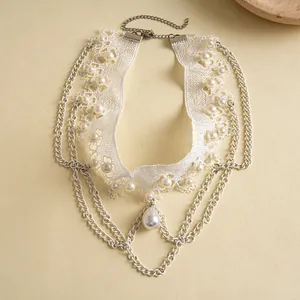 Detailansicht eines weißen Spitzen-Chokers mit Perlenakzenten und Kettenfransen