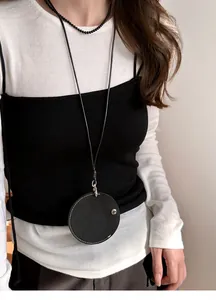 Detail einer Halskette mit rundem Lederanhänger und Brillenhalter am Modell.