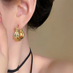Elegante goldene Creolen mit Hochglanzfinish, getragen an einem Modellohr.