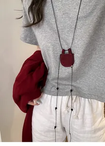 Detailansicht einer weinroten Wildleder-Halskette getragen über einem grauen T-Shirt.