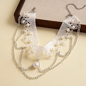 Detail eines weißen Spitzen-Chokers mit Perlen und mehrlagigen Kettenquasten