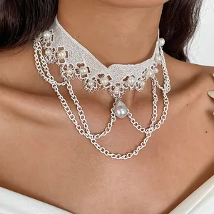 Detailaufnahme eines weißen Spitzen-Chokers mit Perlen und mehrlagigen Kettenanhängern