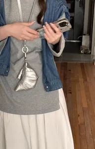 Detailansicht eines silbernen Anhängers in Croissant-Form an einer Lederband-Halskette