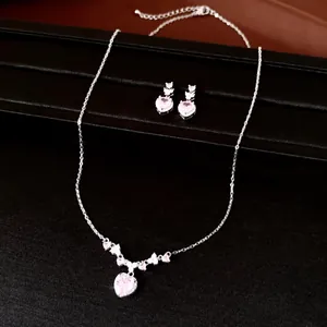 Detail van zilverkleurige sieradenset met roze hart zirkoon ketting en bijpassende oorbellen.