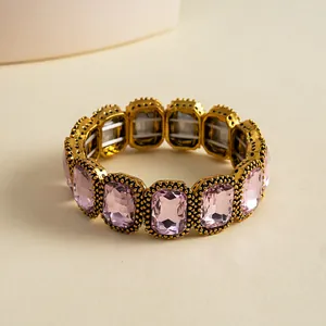 Detail view of a vintage pink square crystal elastic bracelet in a gold setting.