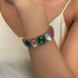 Detail view of a vintage gold bracelet with colorful square crystal stones on wrist