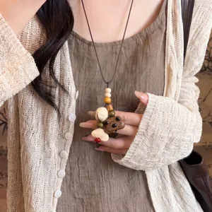 Close-up of vintage wooden bear pendant necklace with leather cord worn on a model