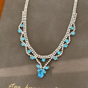 Detail van blauwe zirkoon ketting met waterdruppel hanger op een grijze geschenkdoos