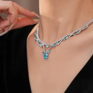 Elegante zilverkleurige ketting met blauwe zirkoon hanger gedragen door een model