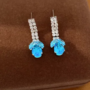 Close-up van elegante blauwe traanzirkonia oorbellen met fonkelende steentjes