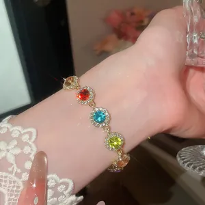 Gros plan d'un bracelet en strass coloré sur un poignet avec chaîne dorée