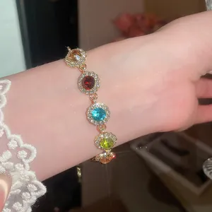 Gros plan d'un bracelet en strass ronds colorés avec monture dorée sur un poignet