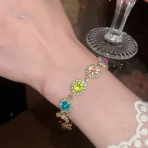 Gros plan d'un bracelet en strass ronds colorés sur un poignet avec une manche en dentelle