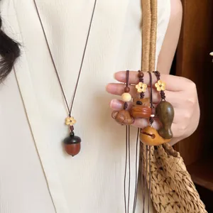Detail van een handgemaakte houten eikel hanger ketting en diverse gesneden houten bedels.