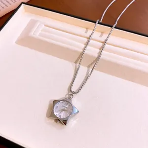 Elegante collana con ciondolo a orologio a stella d'argento su vassoio per gioielli crema