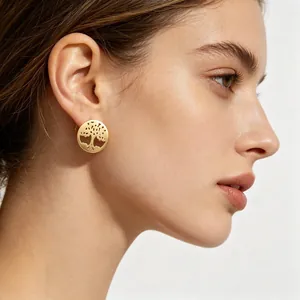 Détail d'une boucle d'oreille dorée Arbre de Vie portée par un mannequin féminin