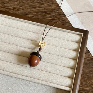 Detailopname van de houten eikel hanger en het kleine bloemdetail van de ketting