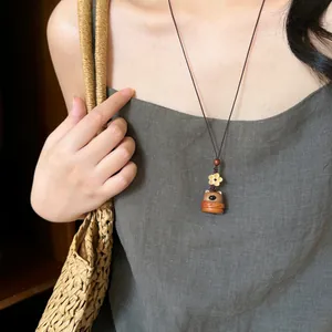 Detail van houten berenhanger ketting met gouden bloem op een groene linnen jurk