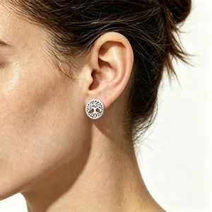 Détail de boucles d'oreilles arbre de vie argentées portées par une femme élégante