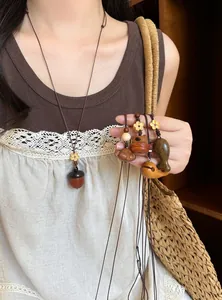 Detailweergave van handgemaakte houten eikel- en dierhangers aan een lange bruine ketting