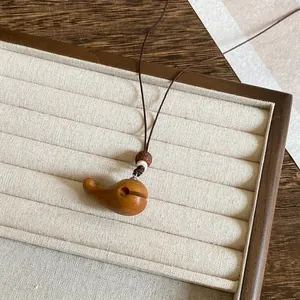 Close-up van een handgemaakte houten walvis hanger ketting op een sieraden display.