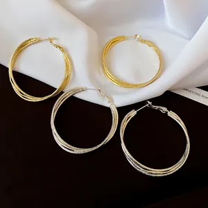 Detailed close-up of textured multi-layered twisted hoop earrings in gold and silver.