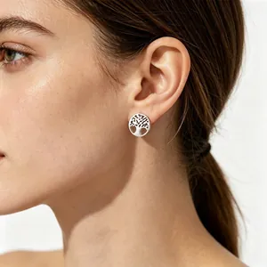 Vue détaillée d'une boucle d'oreille Arbre de Vie évidée en acier titane sur le lobe d'oreille