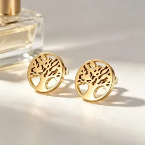 Vue détaillée du motif arbre de vie évidé sur des boucles d'oreilles en acier doré