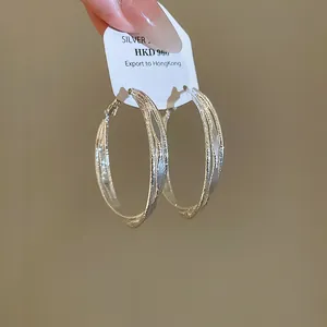 Macro view of elegant three-layer twisted circular silver needle hoop earrings on display