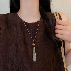 Detail view of a vintage long tassel necklace with stone beads on a brown textured top