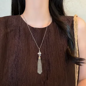 Detail showing a long stainless steel tassel necklace with beads on a pleated dress