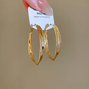 Detail shot of elegant triple-layered twisted gold hoop earrings on a white card.