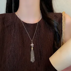 Close-up detail of a vintage stainless steel tassel necklace with beads on a model
