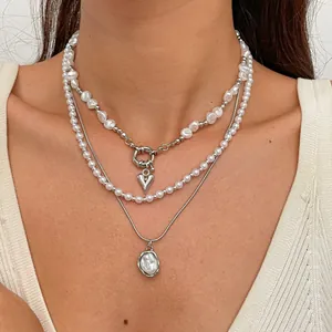Gros plan d'un ensemble de colliers en perles rétro à trois rangs avec pendentifs