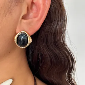 Nahaufnahme von goldenen Vintage-Ohrringen mit dunkel marmoriertem Acryl-Inlay