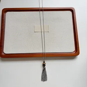 Detail of a vintage stainless steel necklace with stone beads and a chain tassel.
