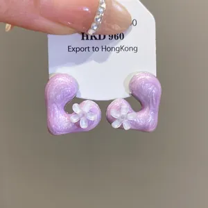 Close-up view of purple resin heart-shaped earrings with delicate white flower detail