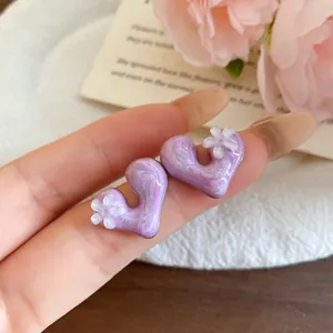 Close-up detail of purple marbled resin heart earrings with delicate white flower charms
