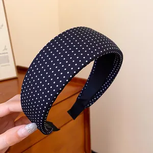 Detailed close-up of a black fabric headband with a white polka dot pattern.