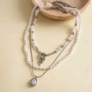 Détail d'un ensemble de trois colliers de perles vintage avec des pendentifs élégants.