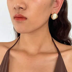 Detailansicht eines goldumrandeten ovalen Ohrsteckers im Vintage-Stil am Modell