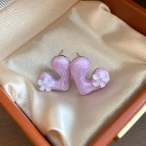 Close-up of pink resin heart earrings with delicate white flower details