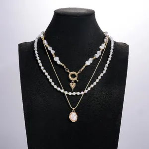 Vue détaillée d'un ensemble de colliers vintage à trois couches en perles et or avec cœur
