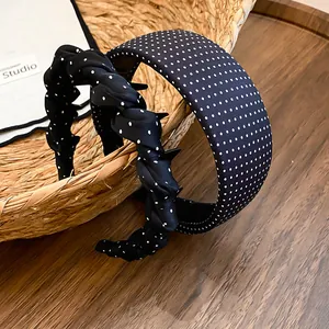 Close-up detail of black polka dot fabric headbands in twisted and wide styles.