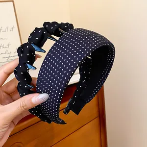 Detailed view of two black fabric headbands with white polka dots and non-slip teeth