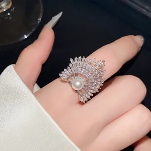 Nahaufnahme eines eleganten fächerförmigen Rings mit Pavé-Kristallen und Perle an der Hand
